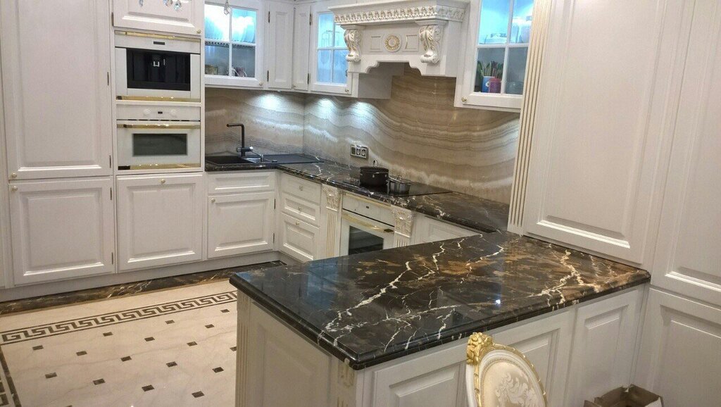 A white kitchen with a black marble countertop