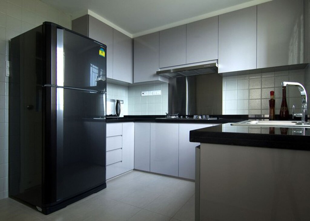 A black refrigerator in the interior of a white kitchen