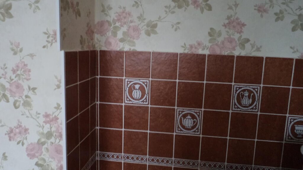 The junction of tiles and wallpaper in the kitchen